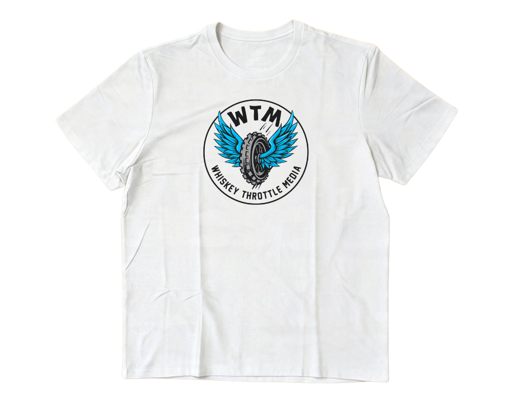  white short-sleeve crewneck t-shirt with a circular graphic on the chest featuring a blue winged tire and the text 'WTM' and 'WHISKEY THROTTLE MEDIA'. The t-shirt is laid flat